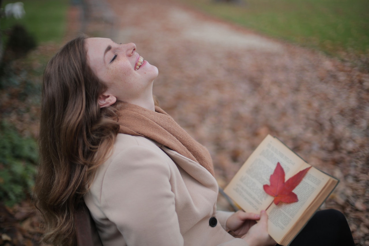 woman reading a book on a park bench