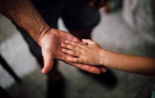child's hand resting in parents hand