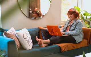 woman sitting on couch working on laptop