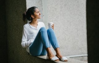 young adult woman sitting down drinking coffee