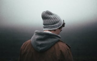 photo of a teenage boy with his back turned towards camera against a blurred out background