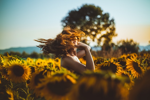woman twirling around in a field of sunflowers