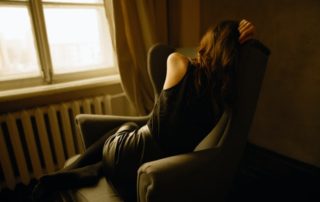 photo of a woman sitting on a chair with her back turned away from the camera