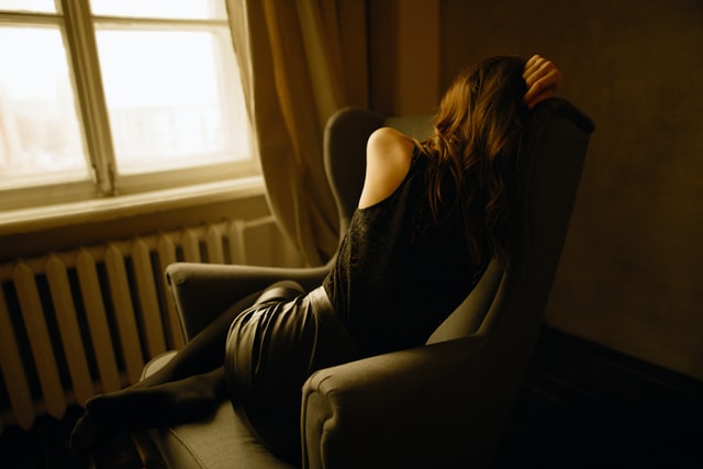 photo of a woman sitting on a chair with her back turned away from the camera