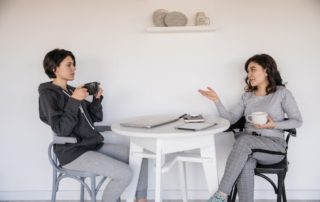 two women talking at a table drinking coffee