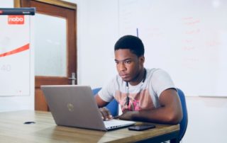 young adult male sitting at a desk working on his laptop