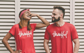 photo of a couple laughing together wearing matching shirts that say thankful