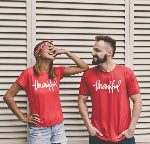 photo of a couple laughing together wearing matching shirts that say thankful