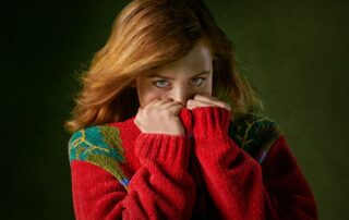 woman in a red sweater pulling it up to cover her face partially