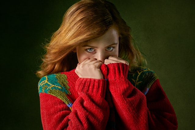 woman in a red sweater pulling it up to cover her face partially