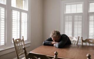 Man in Gray Long Sleeve Shirt Sitting on Brown Wooden Chair