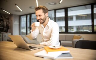 Man Sitting on Chair While Holding Cup in Front of Table