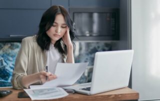 woman working with a laptop and holding a paper