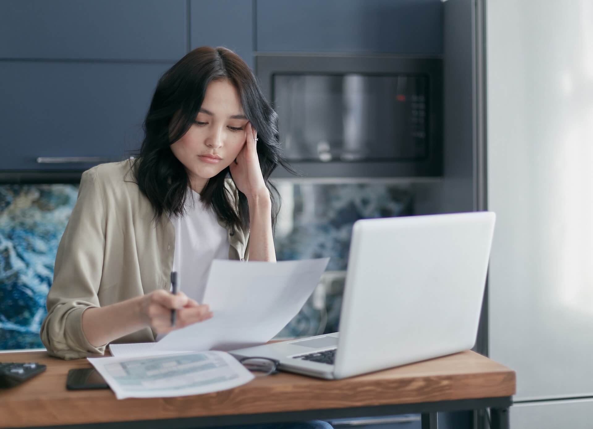 woman working with a laptop and holding a paper