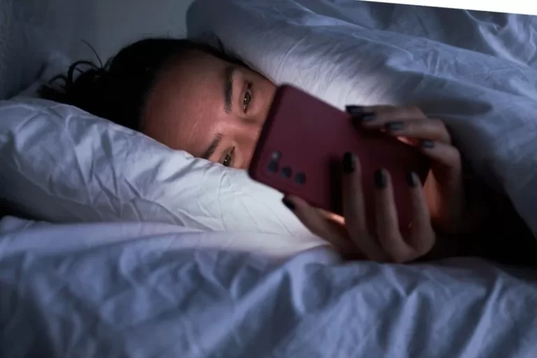 woman using phone in bed