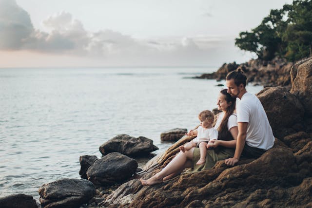 man-and-woman-sitting-on-rock-near-seashore