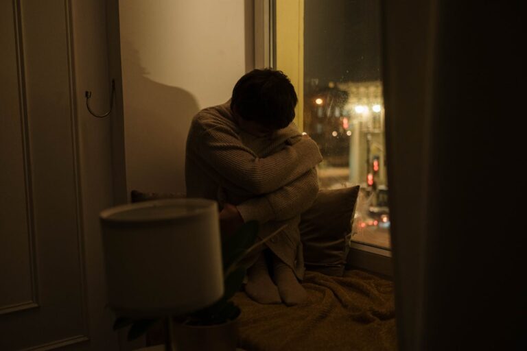 woman-sitting-by-a-window-hugging-her-knees