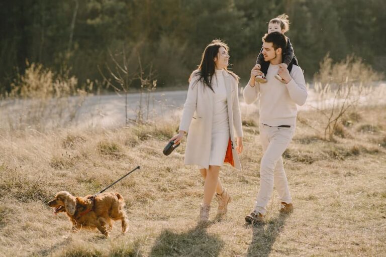 family-walking-on-grass-field-with-their-dog