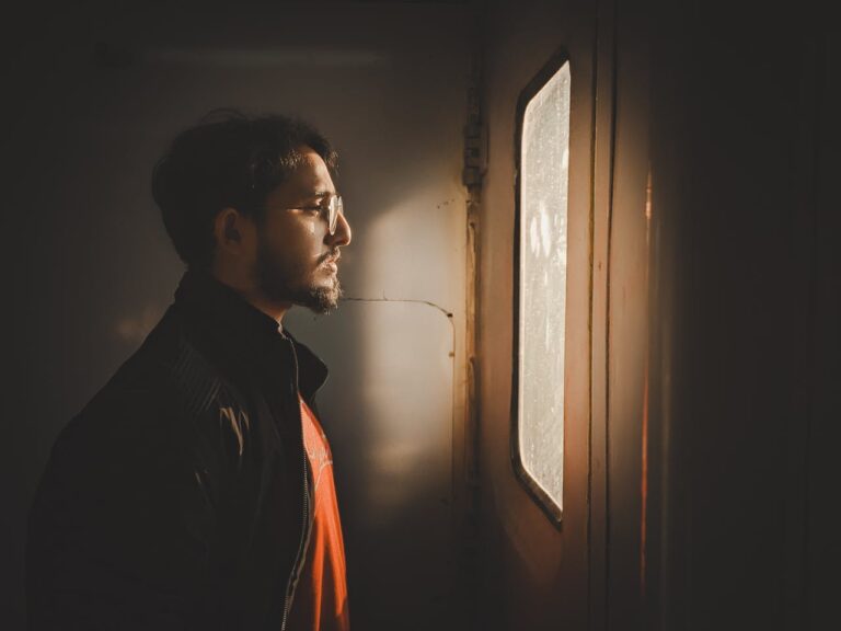 pensive-man-gazing-out-window-in-warm-light