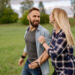 couple-holding-hands-while-walking-on-green-grass-field