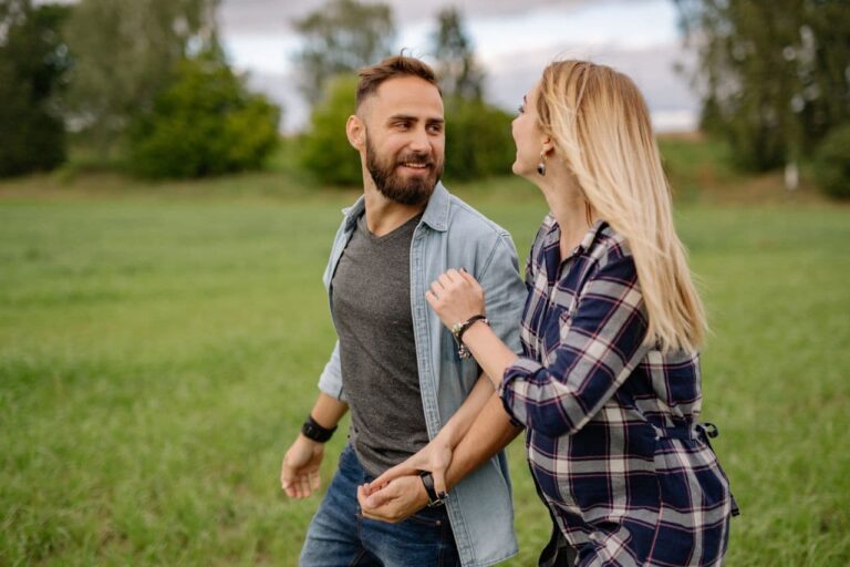 couple-holding-hands-while-walking-on-green-grass-field