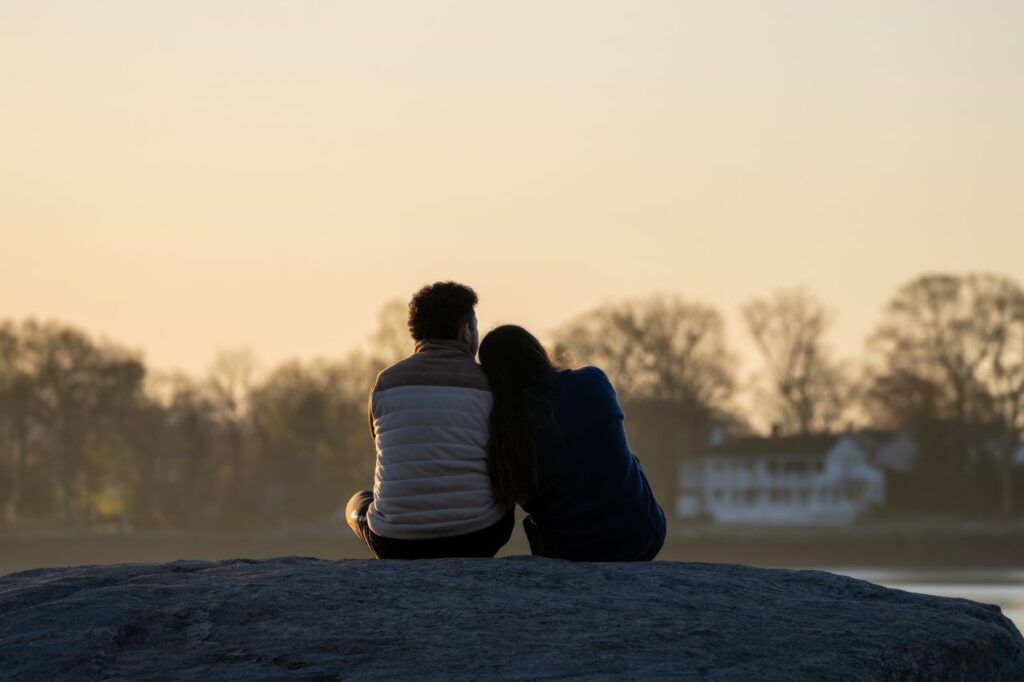couple-enjoying-sunset-on-rocky-shore