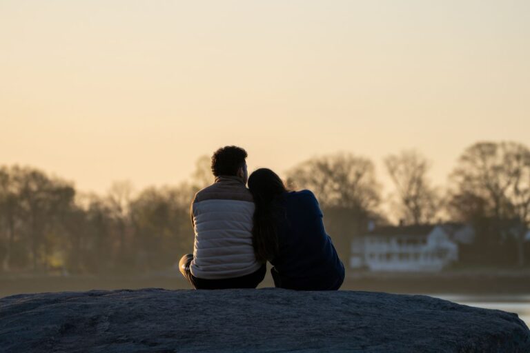 couple-enjoying-sunset-on-rocky-shore